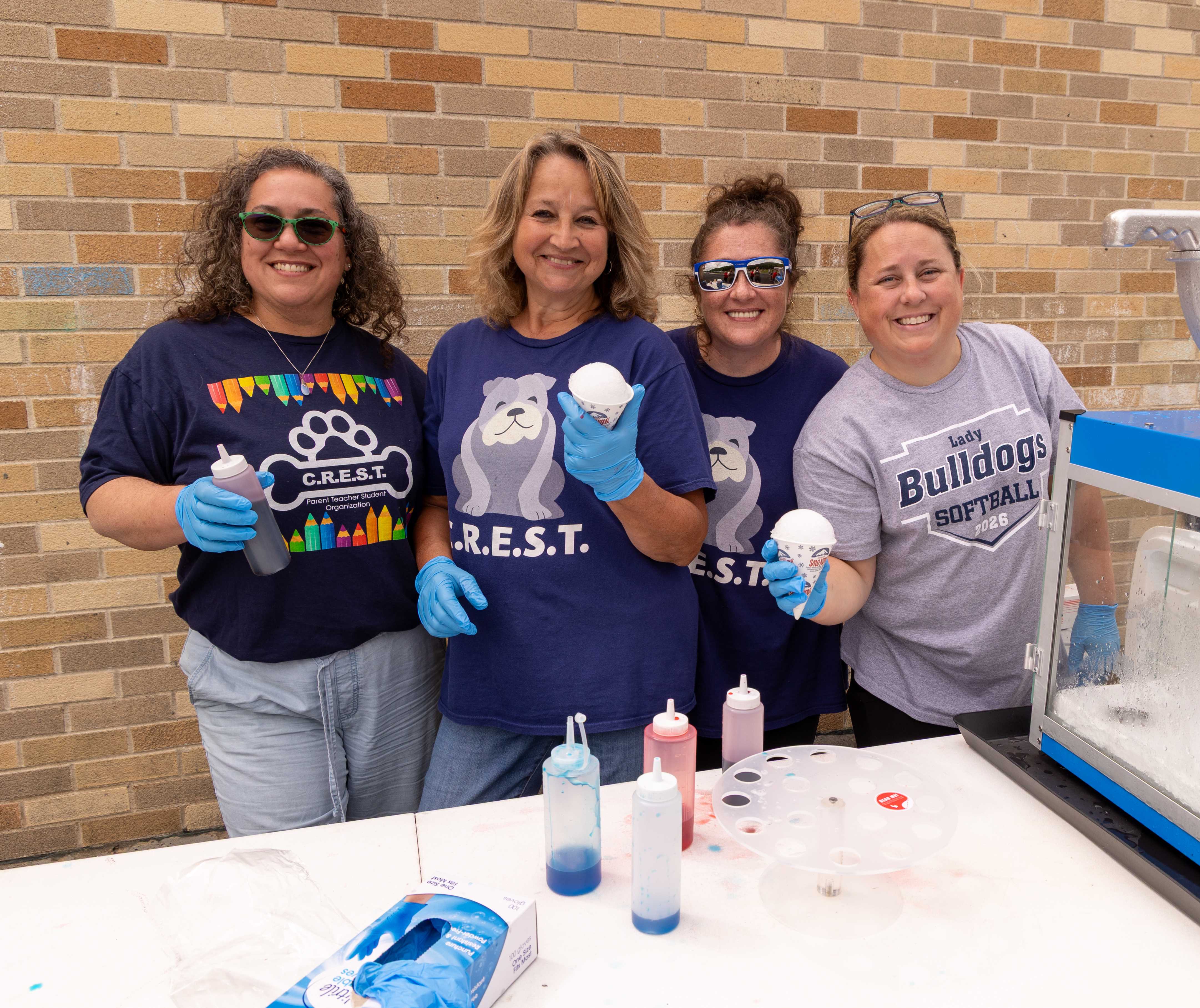 4 CREST volunteers smile holding snow cones